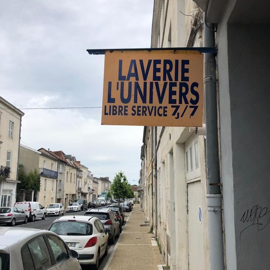 Enseigne drapeau Laverie L'Univers Libre Service 7j/7 dans la rue des Mobiles de Coulmiers