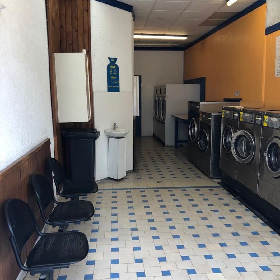 Espace d'attente de la laverie avec sièges, lavabo et rangée de machines